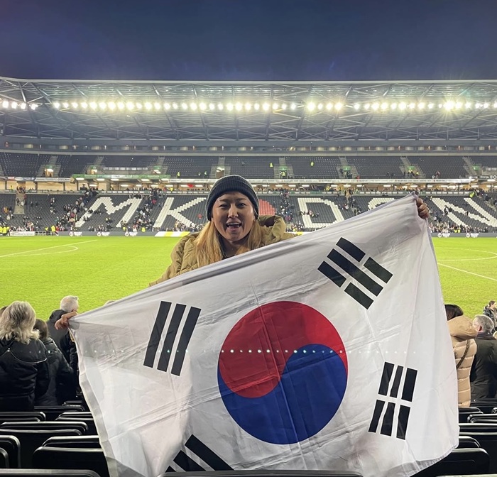 Cho So-hyun holds up a Republic of Korea flag while supporting her team from the stands in Milton Keynes